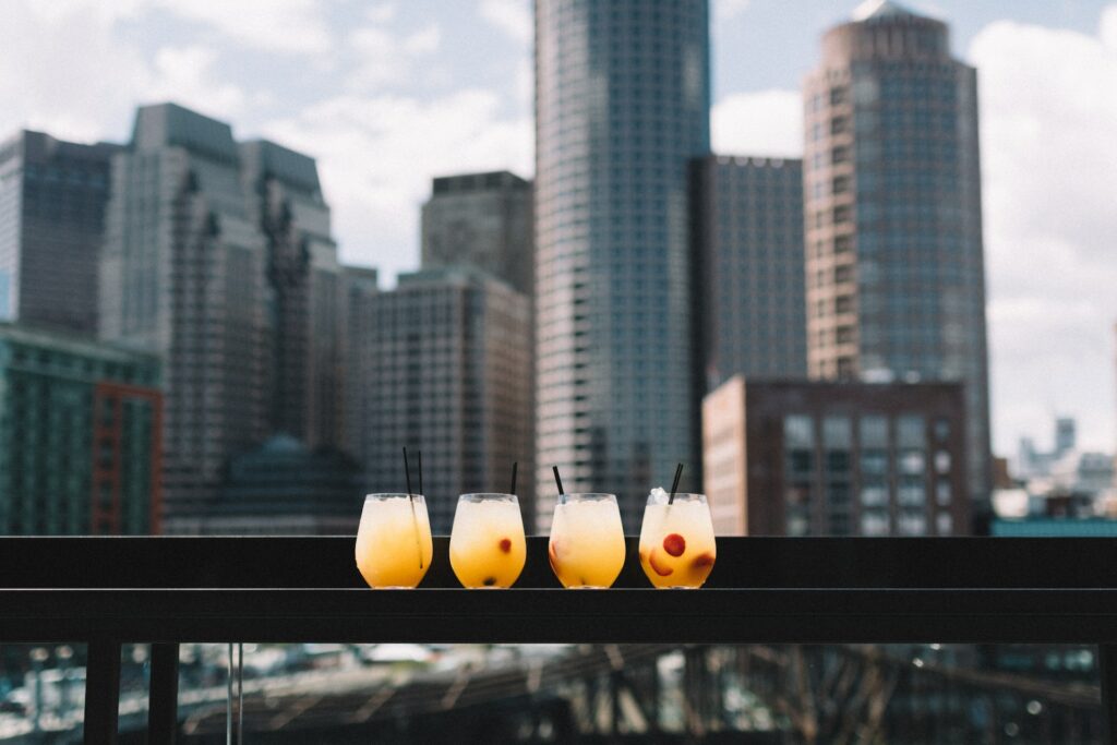 four cocktails stand against the backdrop of the city