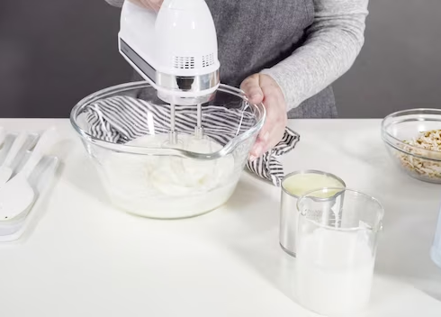 A hand using a hand mixer to whip cream