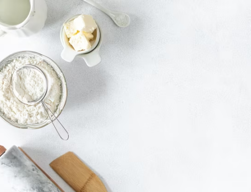 a marble rolling pin with flour, butter, and milk on a white background