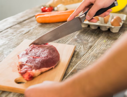 Image of meat being sliced on a wooden board