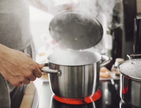 Man cooking and uncovering a pot with steam