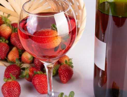 Bottle of rose wine and crystal glass along with strawberries