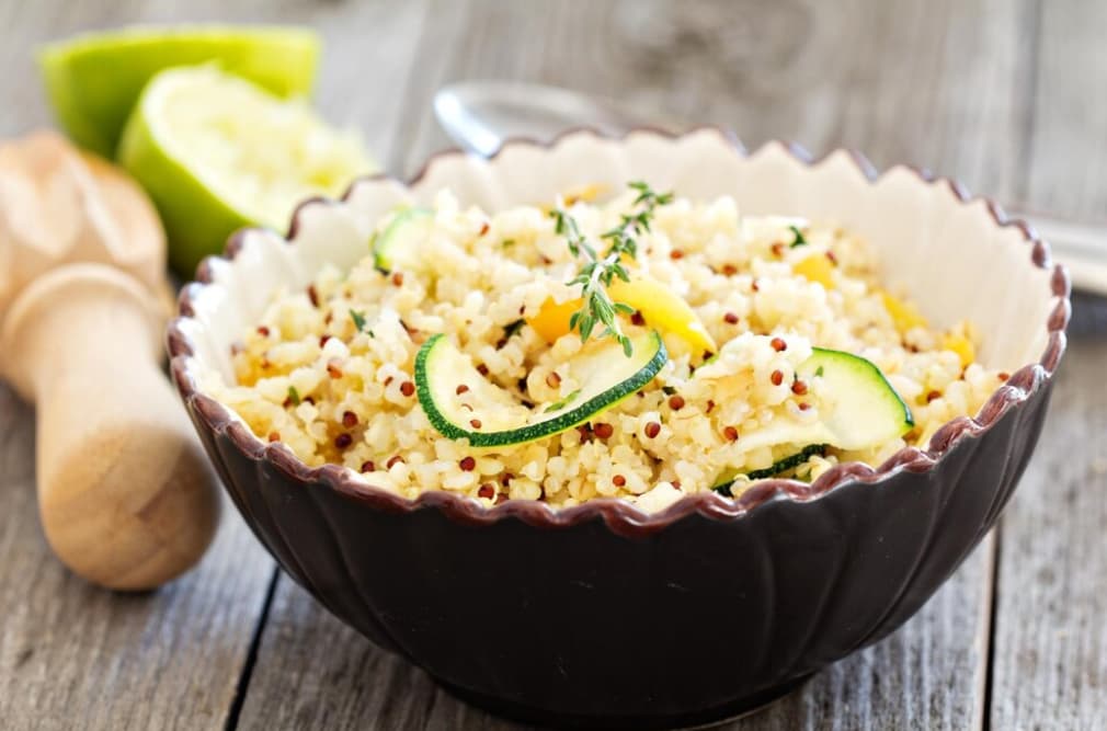 a bowl of quinoa with sliced cucumber, a lime, and soon behind on the blurred fond