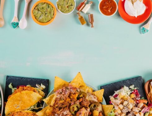 An assortment of Mexican food, including tacos and nachos, on a teal table
